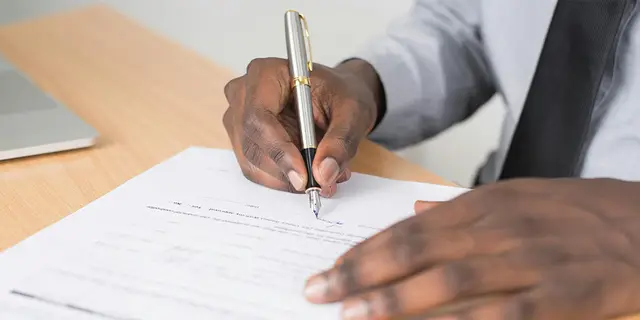 A recorded property document being signed — the kind of instrument a deed copy reproduces, showing the grantor, grantee, legal description and vesting as filed with the county